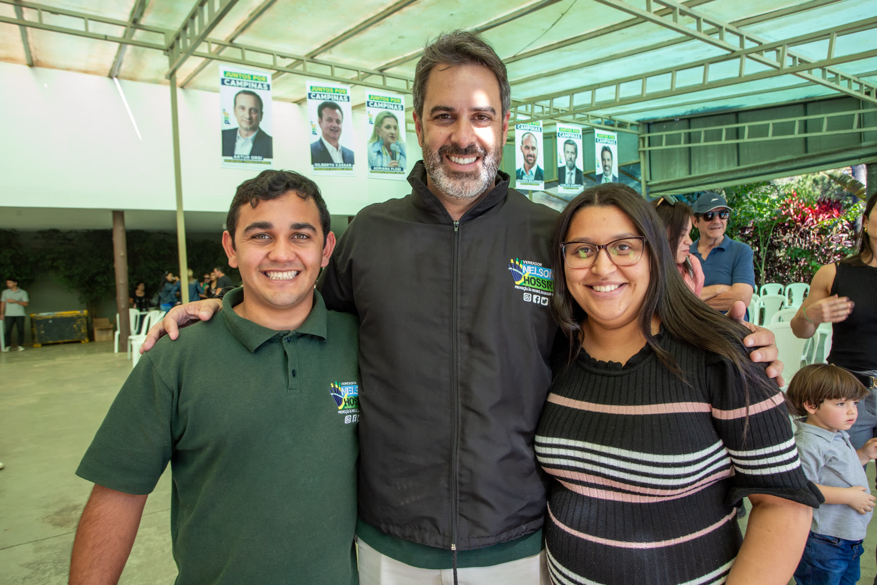 Nelson Hossri entre um rapaz e uma moça, sorrindo, em um encontro de campanha em Campinas