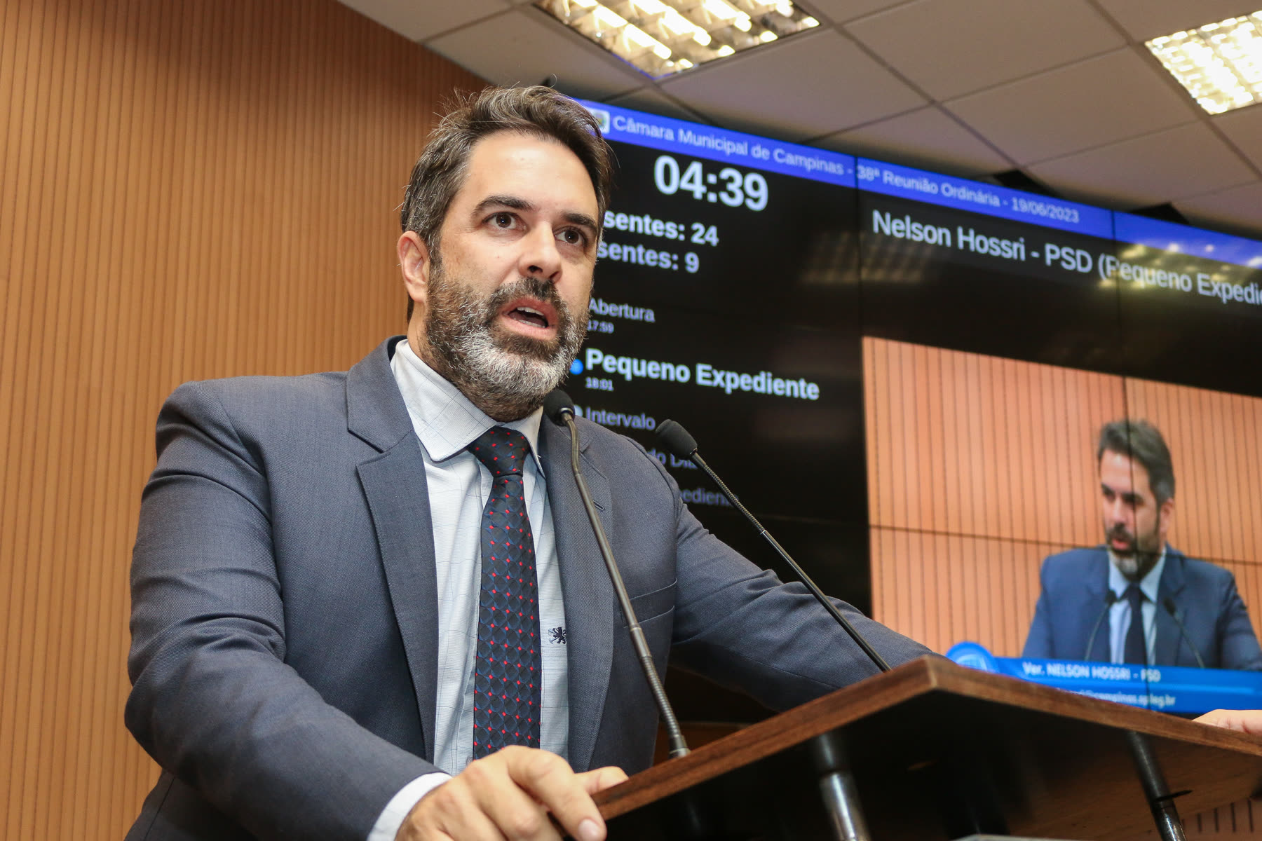 Nelson Hossri na tribuna da Câmara Municipal de Campinas, com o nome no painel ao fundo